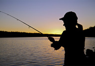 Silhouette of female angler at sunset