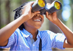 A boy watching birds through binoculars with a big smile