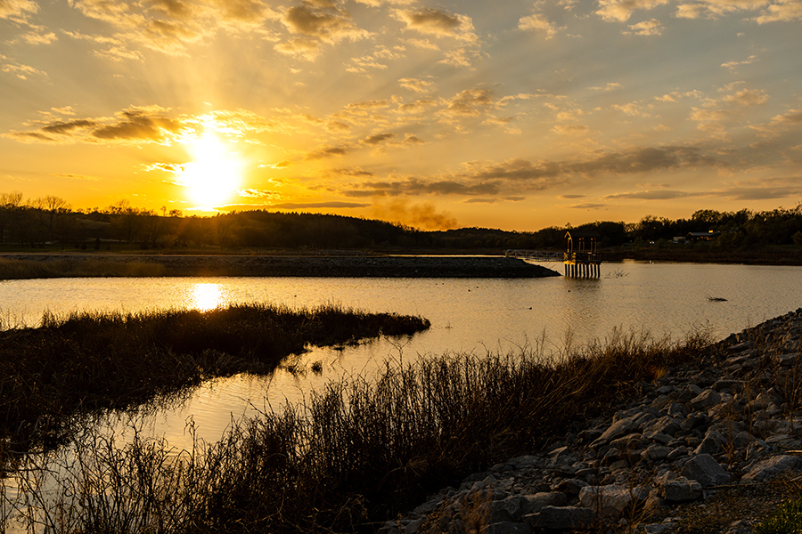 A golden sunset shines over fishing pier and lake at Summit Lake State Recreation Area.