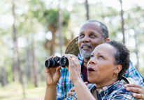 Senior couple smiling and looking at birds through binoculars