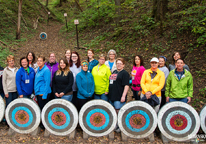 Women standing next to archery targets in a forest