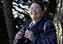 Portrait of Cassandra Dean smiling and holding binoculars