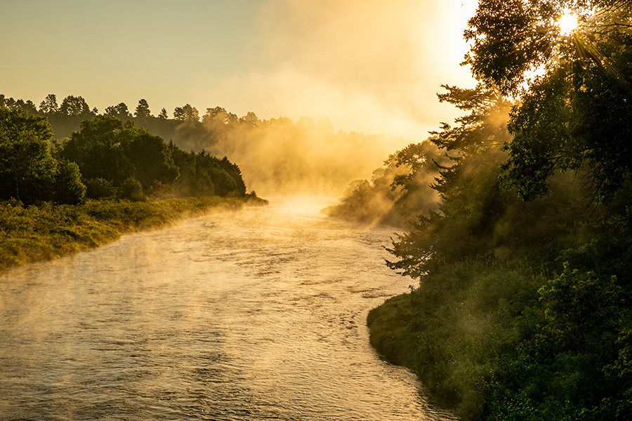 Golden light and fog streams over the Niobrara River at sunrise.