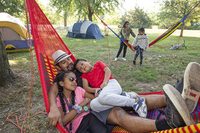 Father and kids cuddle on a hammock at Louisville State Recreation Area