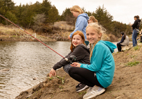 Girls fishing along a bank