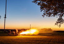 A cannon being fired at night, with burst of smoke and flame