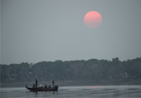 People boating and fishing at Box Butte Reservoir at dusk with red sun above