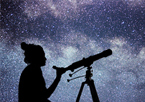 Silhouette of girl using telescope with a bright star-filled sky