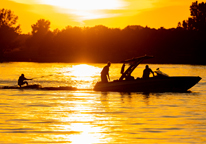 A boat pulls a wakeboarder at sunset at Branched Oak State Recreation Area