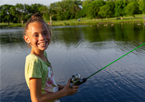 Girl smiling at the camera while fishing during a family fishing night in Omaha