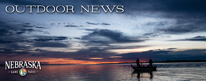 Boaters on a lake at sunset with text, "Outdoor News" and the Game and Parks logo