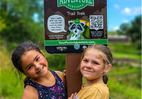 Two girls standing by a Your Parks Adventure sign