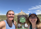 Two young women standing by a selfie sign with Chimney Rock in the background