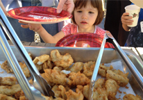 A young girl waits for her helping of fried fish at a Game and Parks event