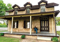 A reenactor sits outside the Commanding Officer's Quarters at Fort Hartsuff.