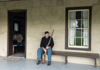 Reenactor sitting on a bench outside a building at Fort Hartsuff