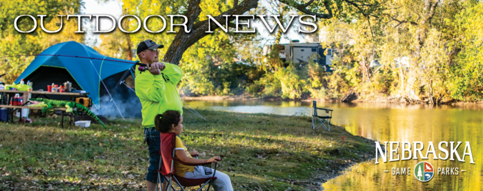 Father and son fishing by their campsite with fall color behind them