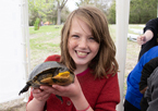 A girl smiles and holds up a turtle at a Nebraska Game and Parks expo