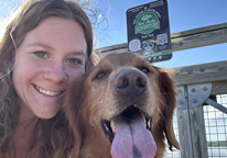 Young woman and her dog posing by a Your Parks Adventure sign