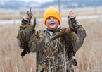 A boy holding up pheasants he harvested