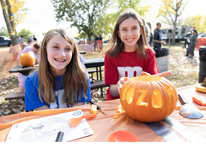 Girls carving pumpkins at Branched Oak's Halloween event