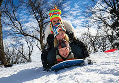 Family piled on a sled, smiling and laughing