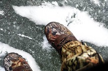 Closeup of man wearing ice-fishing boots standing on ice