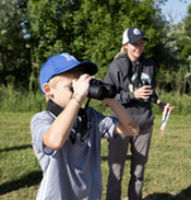 A boy looking for birds through binoculars