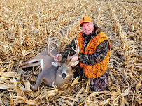 A hunter poses alongside a harvested deer