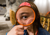 A girl looks through a magnifying glass