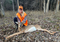 A hunter posing next to a harvested button buck