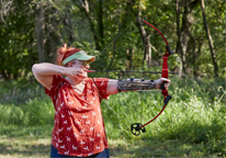 A woman aims her bow on an archery range