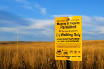 A field with a yellow Open Fields and Waters sign posted on it