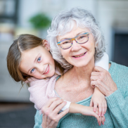 A young girl has her arms wrapped around her grandmother as they both smile.