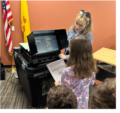 Clerk Clark helping a kid cast a ballot 