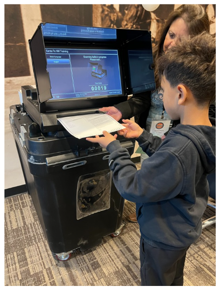 Kid casting a ballot at a tabulator