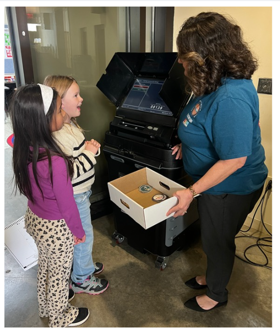 2 THRIVE students at a tabulator, talking with a pollworker