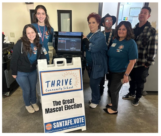 Santa Fe County Clerk's Office Staff posing in front of tabulators and event signage