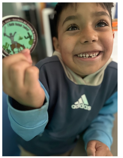 THRIVE student holding an "I Voted" sticker and smiling at the camera