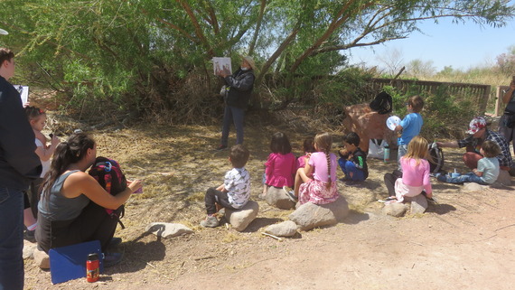 children gathering around to listen to a storybook read by a volunteer