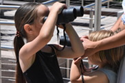 Little girl looking through binoculars on Discovery Day.