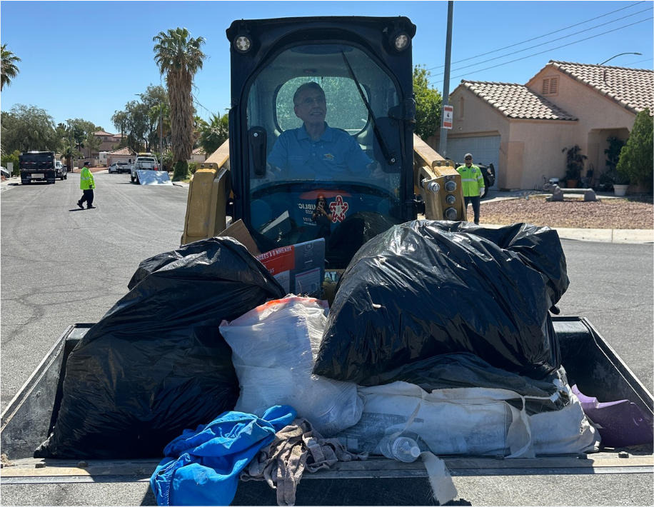 Councilman Cherchio in bobcat carrying trash