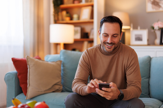 Middle aged male using his smartphone sitting on couch.