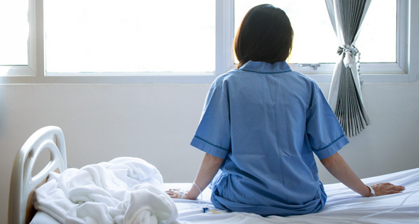 Woman sitting on hospital bed looking out the window