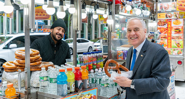 New York State Comptroller Thomas P. DiNapoli purchasing a pretzel from a NYC street vendor.