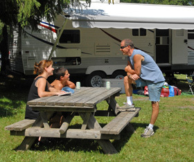 family sitting at picnic table beside camper