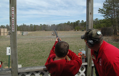 Instructor with boy aiming shotgun