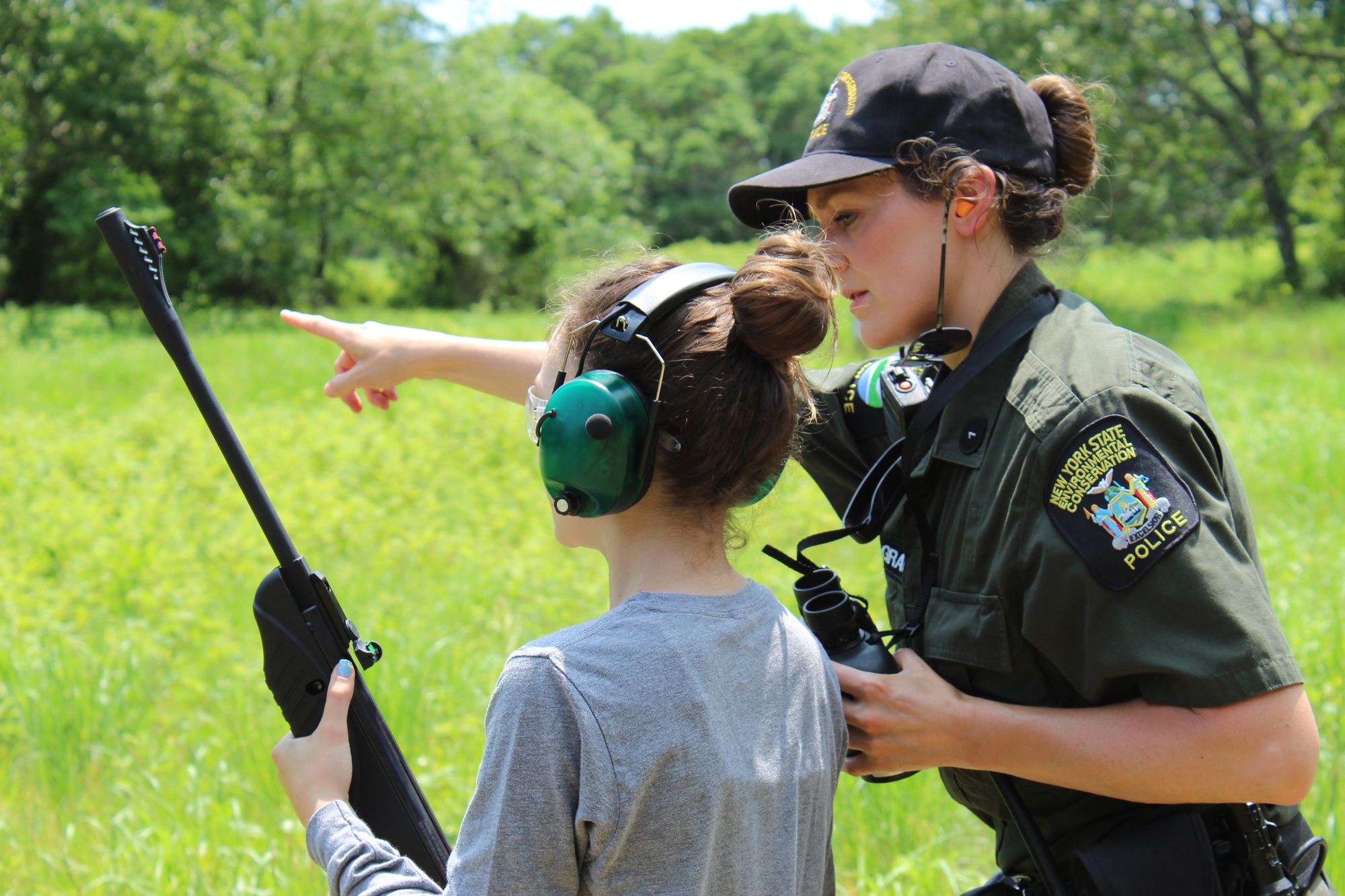 A young woman receives gun safety lessons from a female instuctor in uniform.