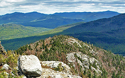 The summit of Bear Den Mountain overlooking the mountainous background of the Adirondack High Peak region on a clear day