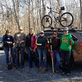 A group of members from CLIMB getting ready to head out and do trail work in front of a car with a mountain bike